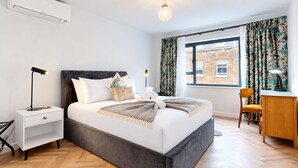 A modern bedroom with a bed, bedside table, lamp, and a view of the outside. - AC! Modern Flat, 5 mins from Angel - Pass the Keys (London)
