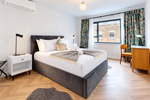 A modern bedroom with a bed, bedside table, lamp, and a view of the outside. - AC! Modern Flat, 5 mins from Angel - Pass the Keys (London)