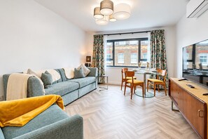Un salon moderne comprenant un canapé, une table à manger, des chaises et un téléviseur.