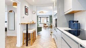 A modern kitchen with a built-in oven, a blue appliance on the counter, and a dining area with a table and chairs. - AC! Modern Flat, 5 mins from Angel - Pass the Keys (London)