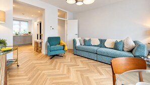 A modern living room with a sofa, armchair, and a dining area with a glass table. - AC! Modern Flat, 5 mins from Angel - Pass the Keys (London)