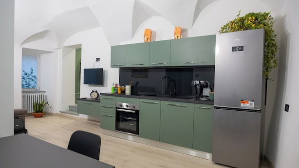 Eine moderne Küche mit grünen Schränken, einem Edelstahl-Kühlschrank und einem eingebauten Backofen.