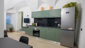 Una cocina moderna con gabinetes verdes, un refrigerador de acero inoxidable y un horno empotrado.
