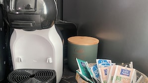 Eine Kaffeemaschine auf einer Küchenarbeitsplatte mit einer Korb voller Kaffeekapseln.