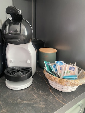 A coffee maker on a kitchen counter with a basket of coffee pods.