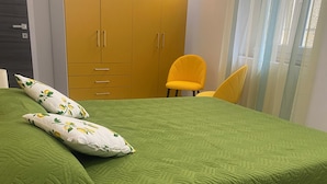 Ein Zimmer mit einer grünen Bettdecke, einem gelben Sessel und einem Wandschrank mit mehreren Türen.