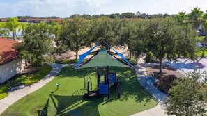 A playground with a green play structure, a bicycle, and a bench. - Bella Vida Family Escape Near Disney (Kissimmee)