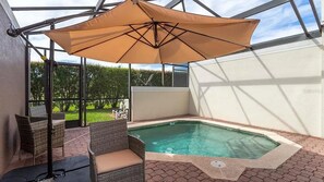 Een overdekt buitengebied met een hottub, rieten meubilair en een grote parasol.