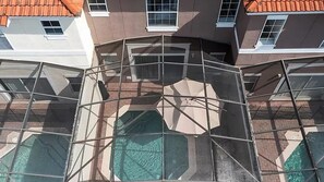 A multi-story building with a glass atrium, multiple windows, and a pool area. - Bella Vida Family Escape Near Disney (Kissimmee)