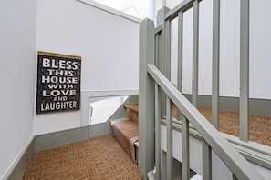 Een trap met een leuning en een bord aan de muur waarop staat 'BLESSED HOUSE WITH LOVE AND LAUGHTER'.