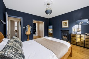 Une chambre à coucher avec un grand lit, une commode, un miroir et une cheminée.