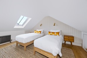 A bedroom with two single beds, a small bedside table, a radiator, and a window. - Stylish Hove Mews | Close to Beach & Station - Pass the Keys (Hove)