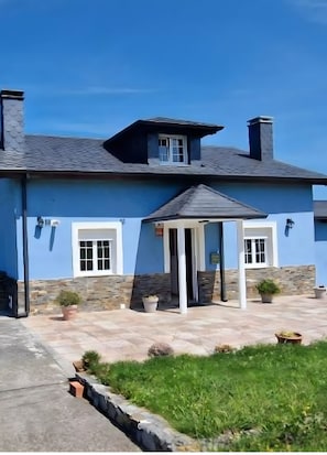A two-story building with a blue exterior, a stone foundation, and a small garden area with potted plants. - Casa Azul: mountain views, private terrace, and Wi-Fi (Quintana)