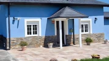 A blue building with a stone facade, a covered porch, and a clear sky.
