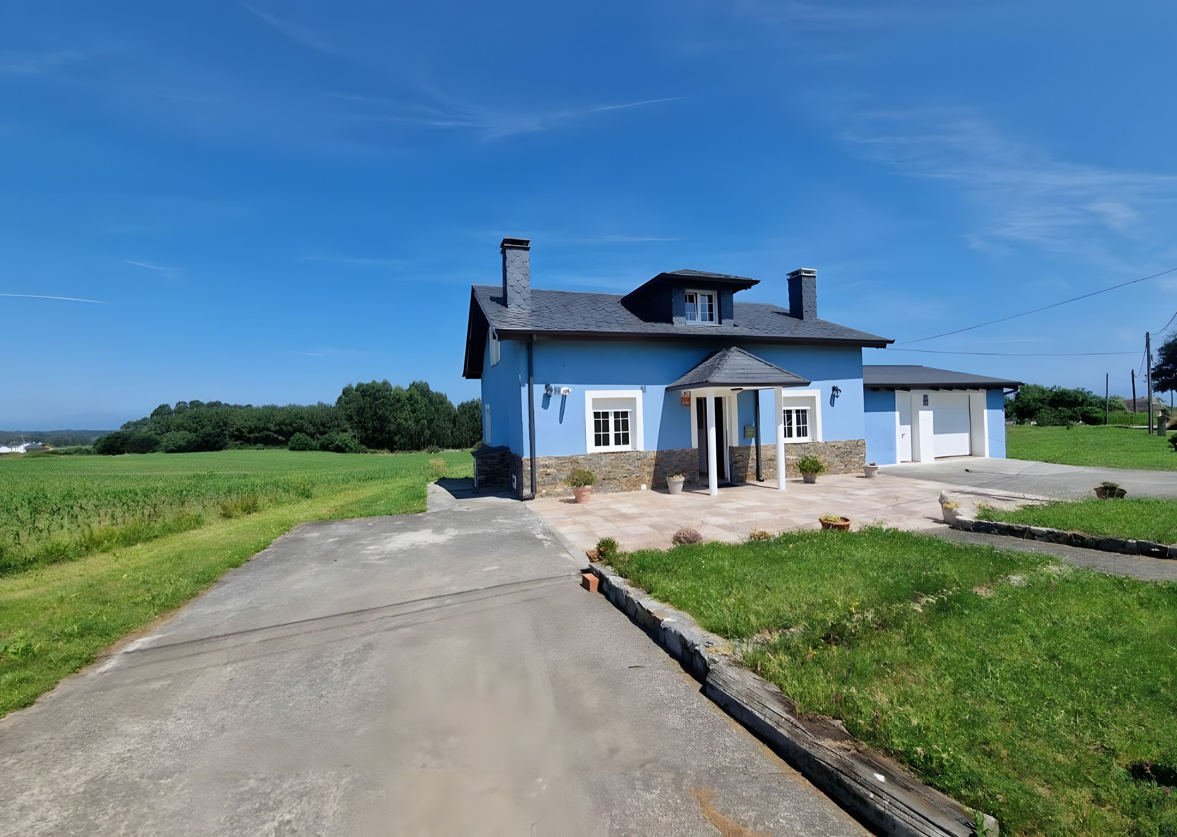 Una casa a due piani con garage, un portico coperto e un vialetto lastricato.