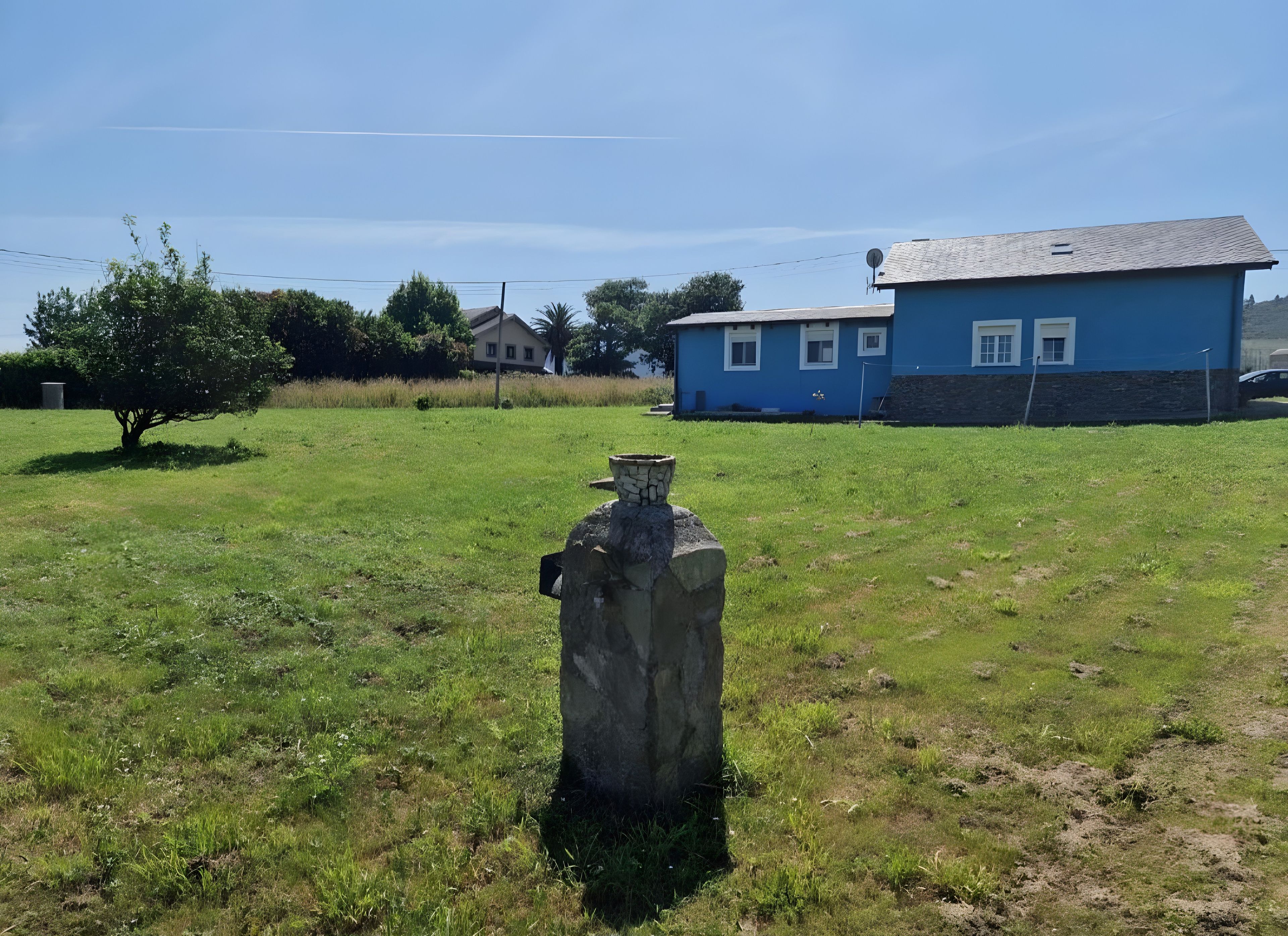 Ein grasbewachsenes Feld mit einem blauen Gebäude im Hintergrund.
