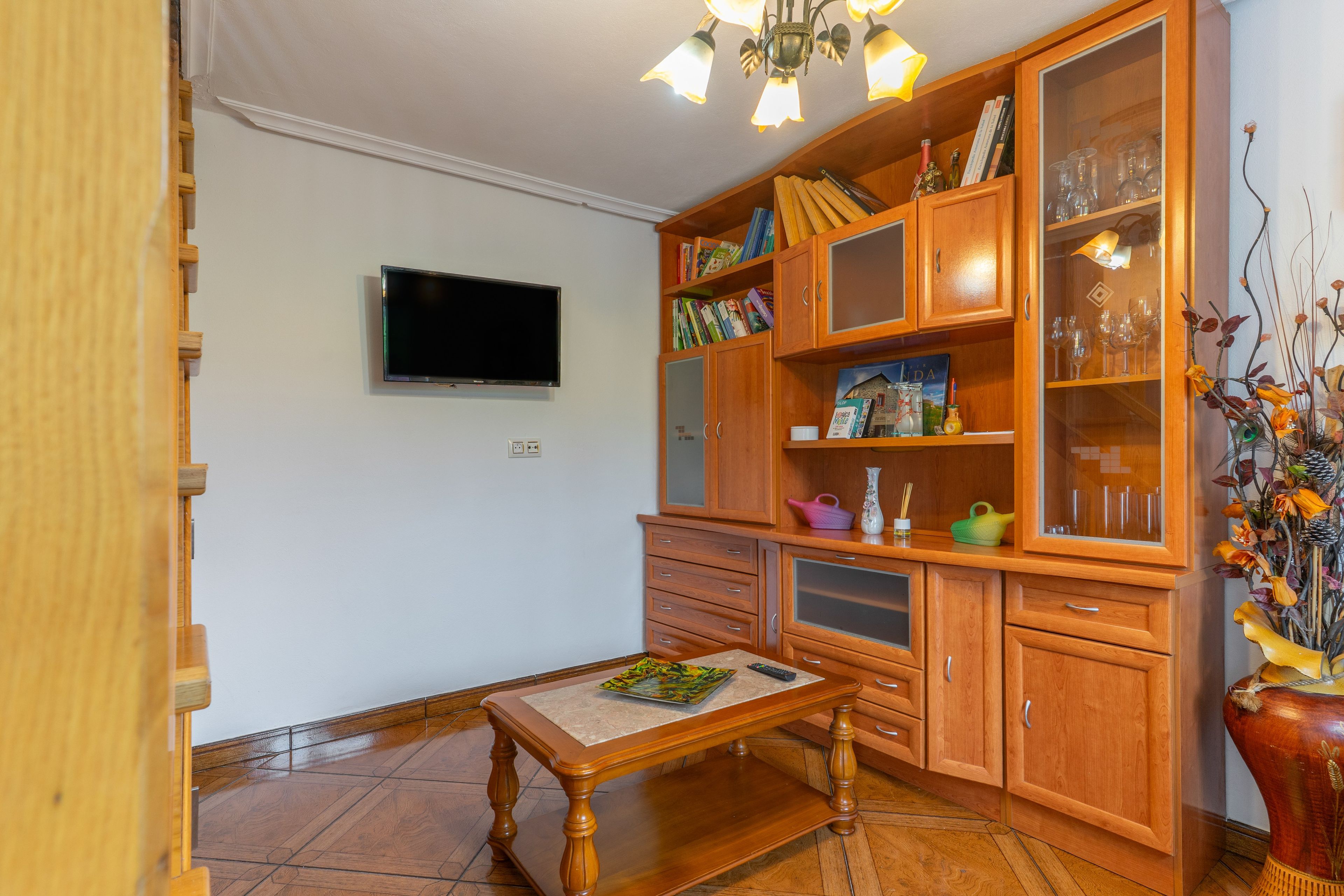 Een kamer met een houten kast, een televisie en een eettafel.