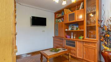 Een kamer met een houten kast, een televisie en een eettafel.