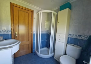 A bathroom with a wooden door, a white sink, a shower enclosure, and a toilet. - Casa Azul: mountain views, private terrace, and Wi-Fi (Quintana)