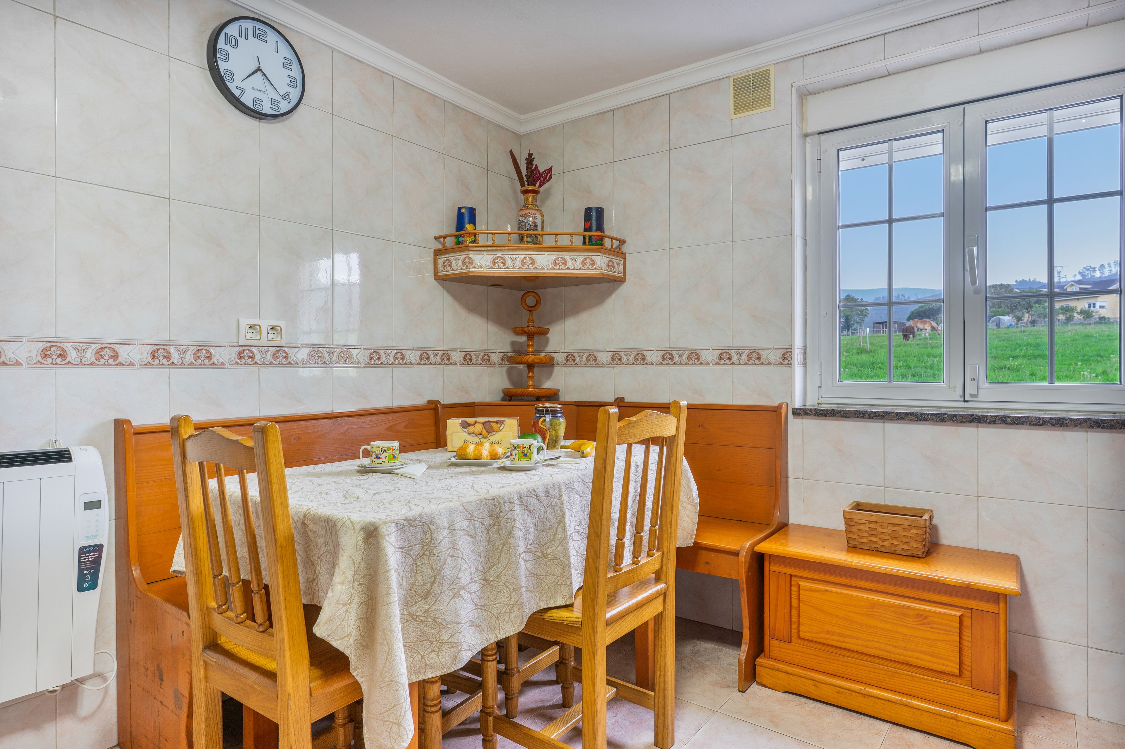 Un comedor con una mesa de madera, sillas, un reloj y un ventanal con vistas al exterior.