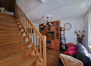 A wooden staircase leading to a living area with a sofa, a bookshelf, and a decorative wall piece. - Casa Azul: mountain views, private terrace, and Wi-Fi (Quintana)