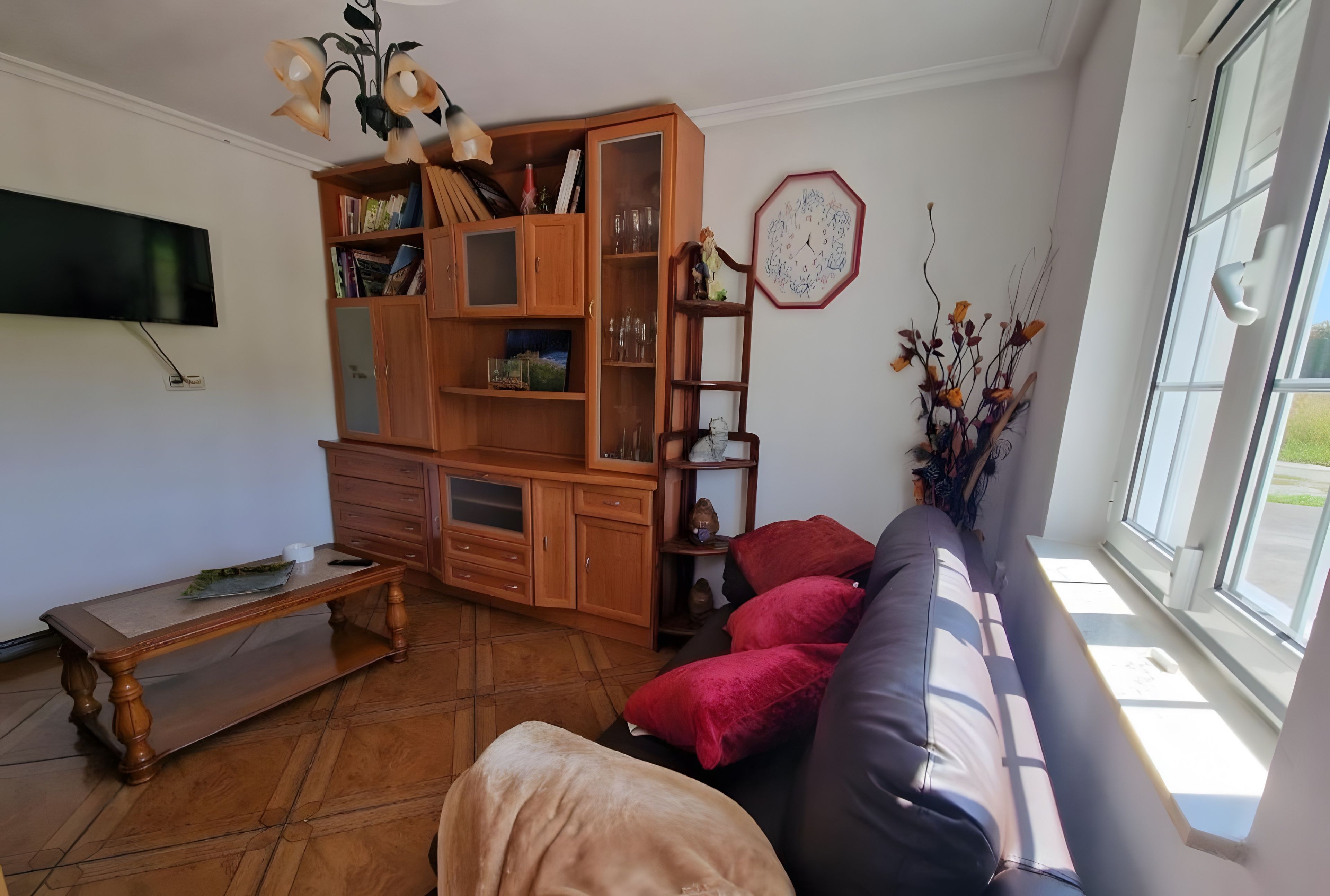 Un soggiorno con un mobiletto in legno, una televisione, un divano e una finestra con vista.