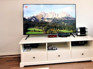 Ein Flachbildfernseher auf einer weißen Unterhaltungsecke, auf dem eine Berglandschaft zu sehen ist.