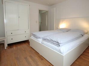 A bedroom with a bed, a wardrobe, and a door. - Holiday Home With 2 Bedrooms (Wyk auf Foehr)