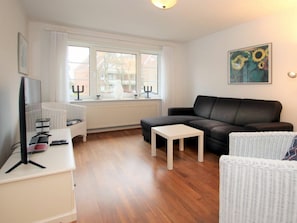 A modern living room with a sofa, a television, a small table, and a wicker chair. - Holiday Home With 2 Bedrooms (Wyk auf Foehr)