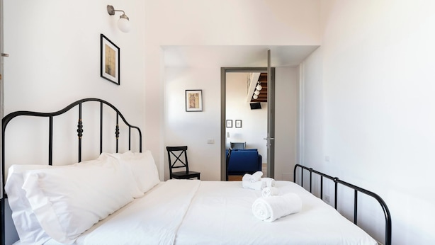 A bedroom with a bed, a chair, a desk, and a television. - Charming Apt in the Heart of Florence (Firenze)
