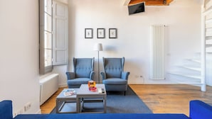 A modern living room with a sofa, armchairs, a coffee table, and a TV mounted on the wall. - Charming Apt in the Heart of Florence (Firenze)