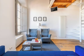 A modern living room with a sofa, armchairs, a coffee table, and a TV mounted on the wall. - Charming Apt in the Heart of Florence (Firenze)