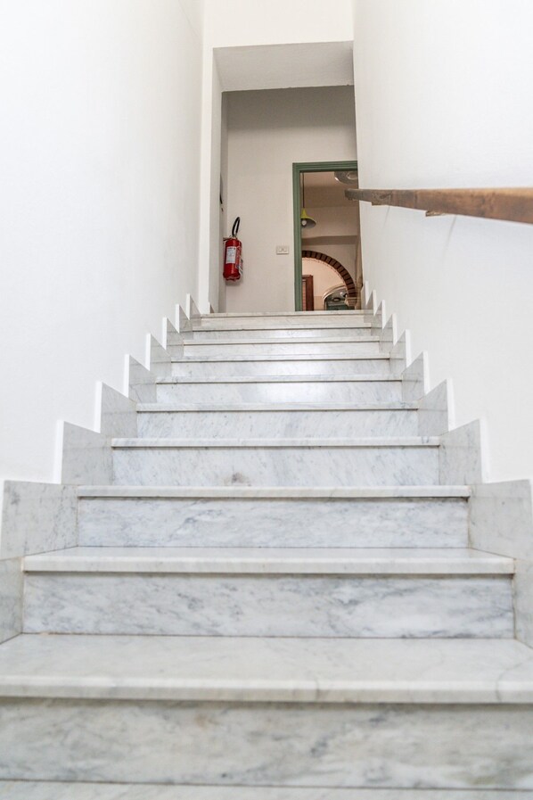 Una escalera de mármol que conduce a un umbral, con un extintor en la pared.