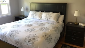 Un dormitorio con una cama, dos mesitas de noche y un ventanal.