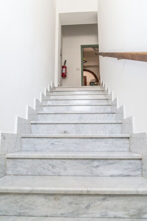 Una escalera de mármol que conduce a una habitación con un extintor de incendios colgado en la pared.