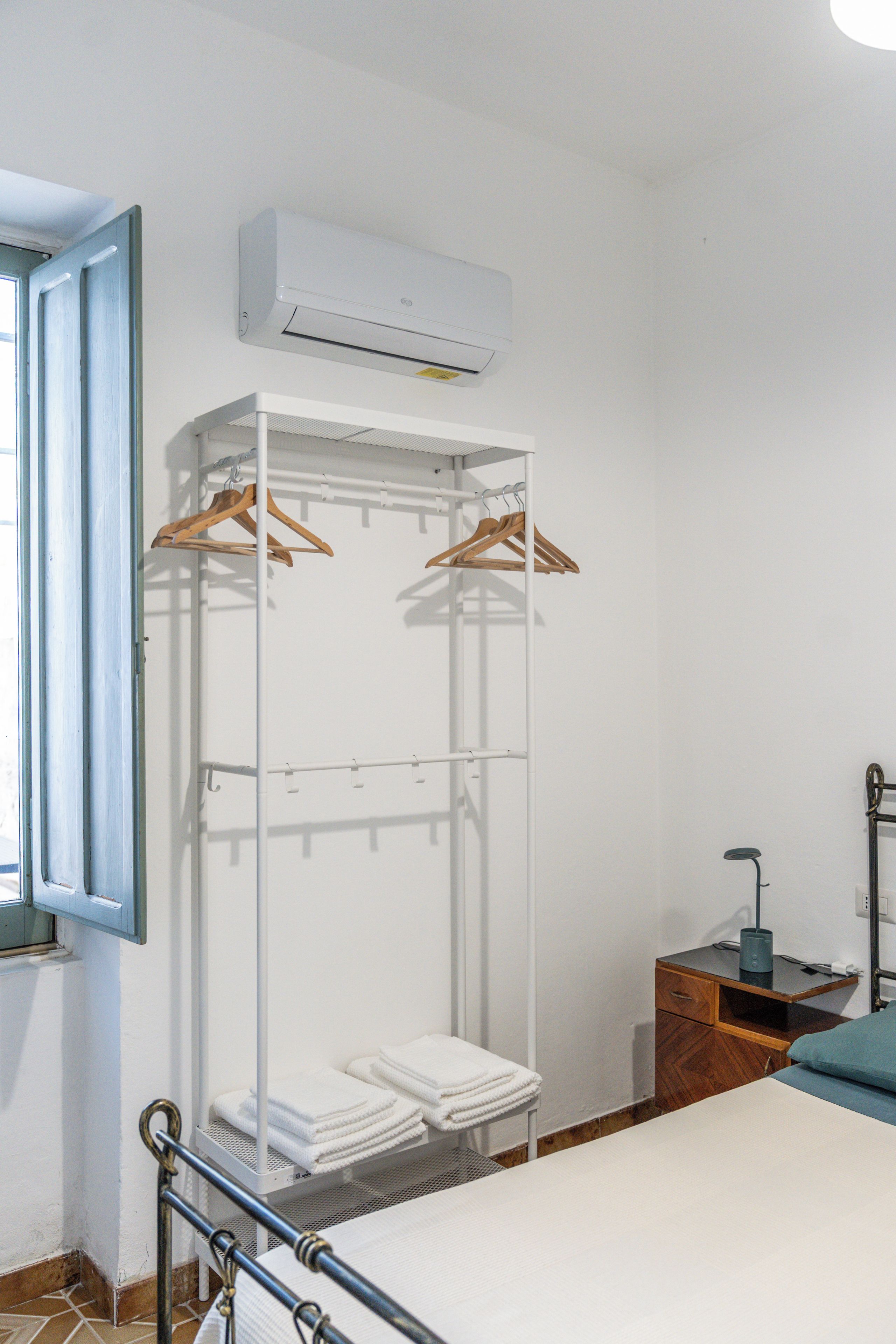 A bedroom with a bed, a wardrobe, a bedside table, and an air conditioning unit.