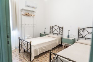 Ein Zimmer mit drei Betten, einem Kleiderschrank und einer Klimaanlage.