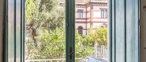 A room with a green door and a view of a tree and buildings outside.