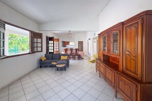 Ein großzügiger Wohnbereich mit grauem Sofa, Holzschrank und Esstisch mit Stühlen.