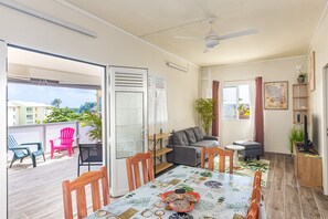 Ein modernes Wohnzimmer mit Esstisch, Sofa und Sesseln. Ein Balkon mit Sitzgelegenheiten und Blick auf die Stadt.