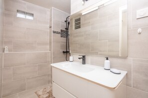 Ein modernes Badezimmer mit großem Spiegel, Waschbecken in Weiß und einer Duschkabine.