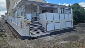 En tvåvåningsbyggnad med en balkong, en trappa som leder upp till övre våningen och en garageport.