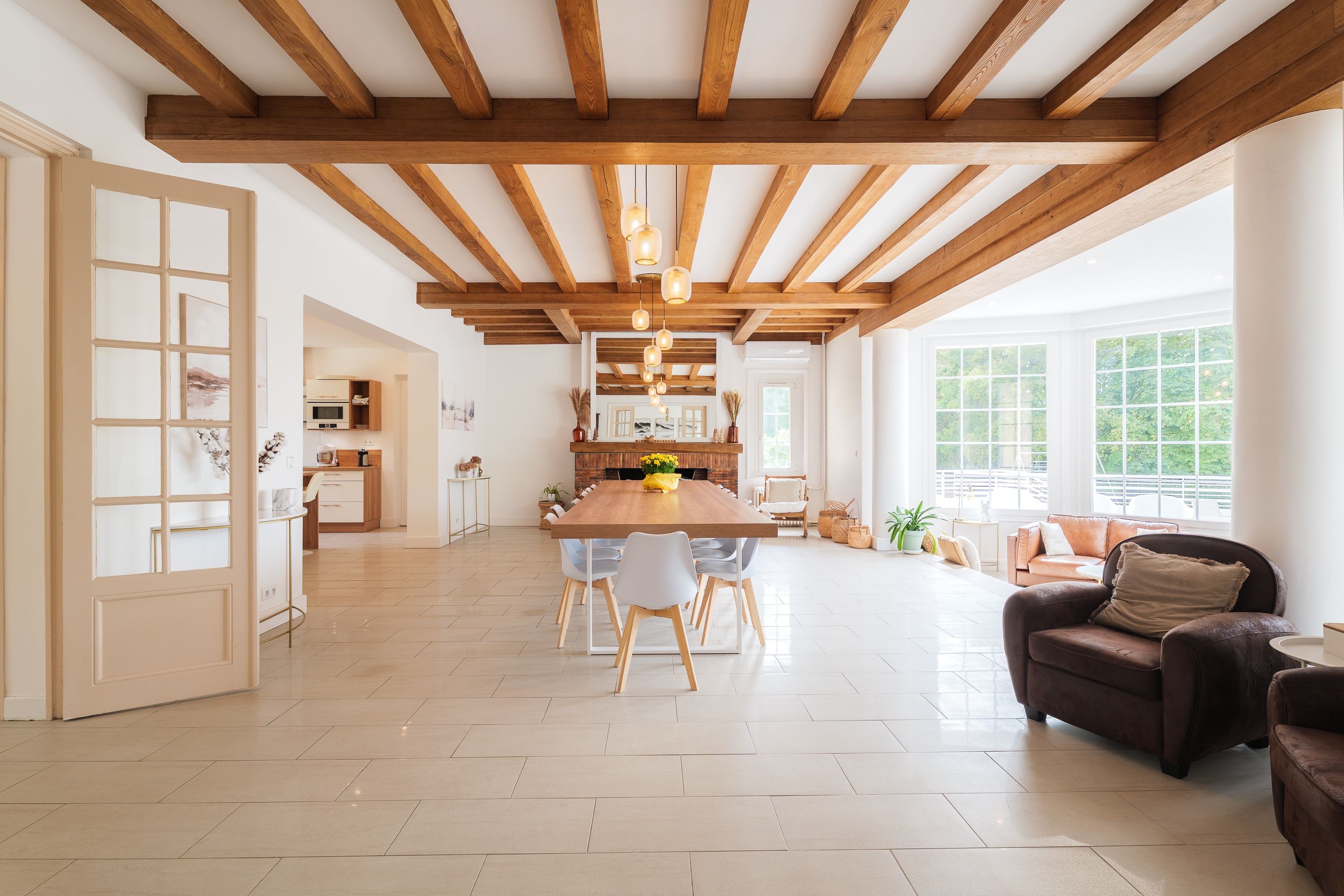A spacious living area with a wooden ceiling, a large dining table, and a sofa.