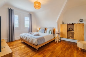 A bedroom with a wooden bed, a nightstand, a lamp, a wardrobe, and a window with curtains. - Les Rouazes - Demeure pour 15p (Mareuil-lès-Meaux)