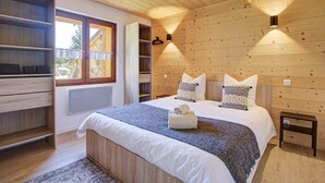 Un dormitorio con una cama grande, un armario empotrado, una ventana y una lámpara fijada a la pared.