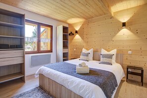 A bedroom with a large bed, a built-in wardrobe, a window, and a wall-mounted light fixture. - Hiona Lodge - magnifique chalet proche stations (Bolquère)