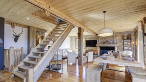 Un interior rústico con escalera de madera, chimenea y comedor.