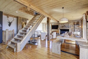 A rustic interior with a wooden staircase, a fireplace, and a dining area. - Hiona Lodge - magnifique chalet proche stations (Bolquère)
