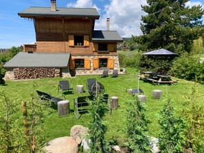 A wooden house with a stone foundation, a stone wall, and a stone chimney. There are outdoor chairs and a picnic table. - Hiona Lodge - magnifique chalet proche stations (Bolquère)