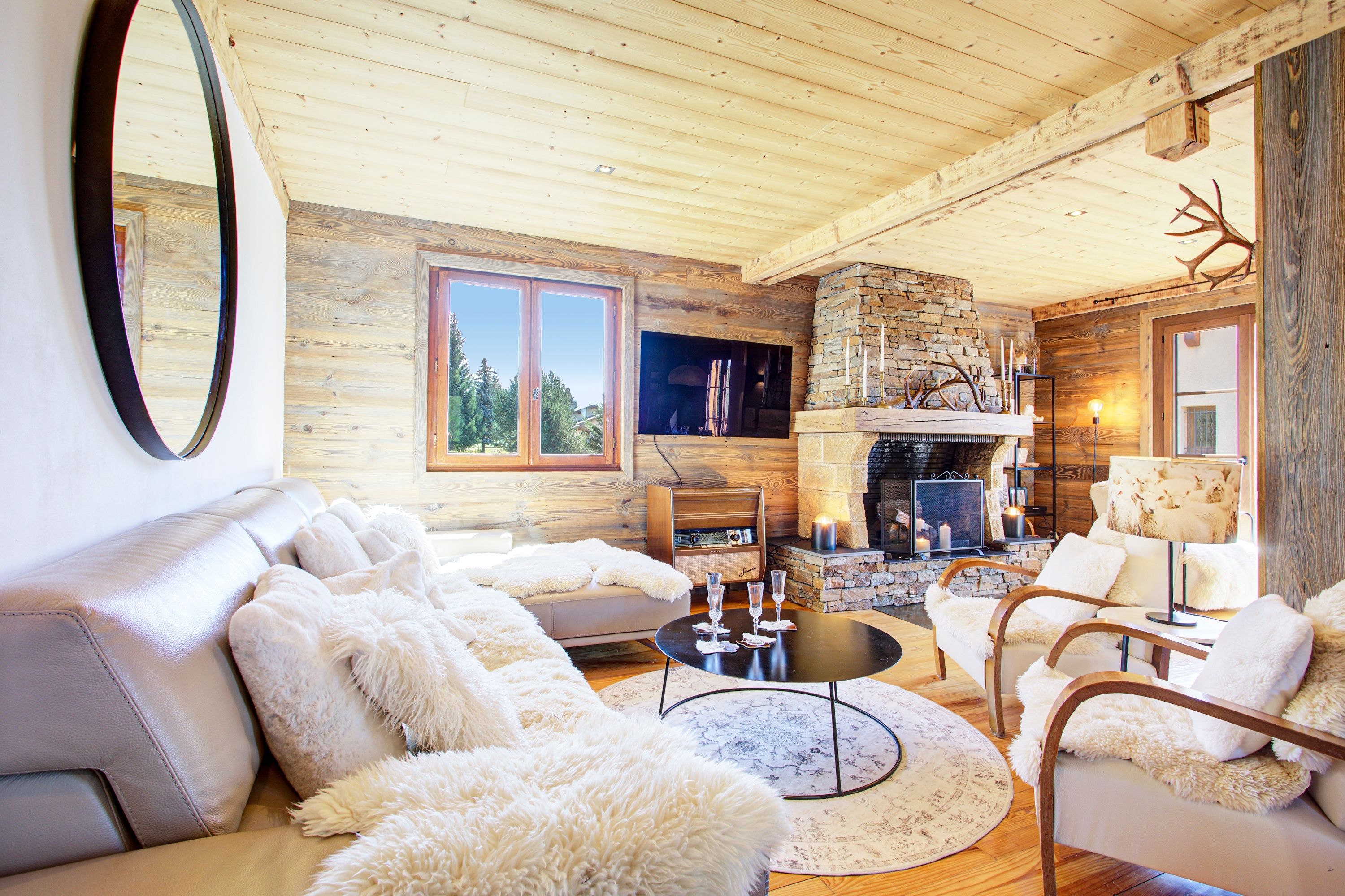 A cozy living room with a stone fireplace, leather sofas, and a large mirror.